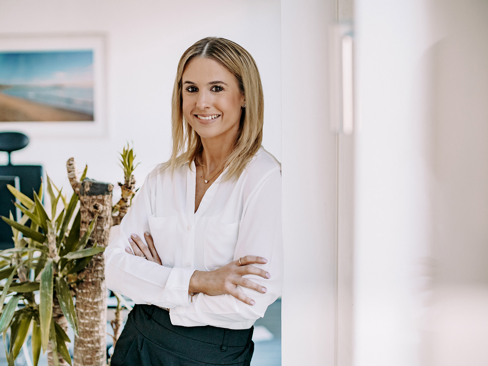 Christina Backer - PINK Wirtschaftsprüfung GmbH Mitarbeiterin Christina Backer lehnt an einer Wand und lächelt in die Kamera. PINK Wirtschaftsprüfung GmbH